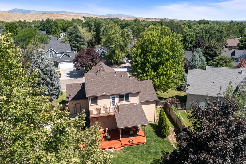 Aerial drone view of a Boise, Idaho, home with a deck, covered patio, and landscaped yard, professionally captured for real estate marketing.