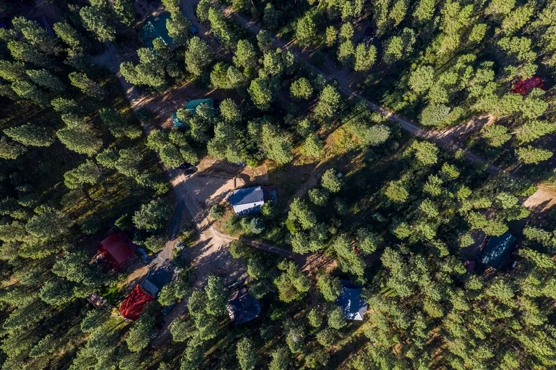 Aerial view of a forested neighborhood in Garden Valley, Idaho, featuring private cabins, dirt roads, and dense pine trees—perfect for real estate and short-term rental marketing.
