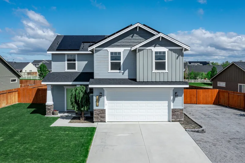 Aerial drone shot of a modern two-story home in Meridian, Idaho, featuring solar panels, a two-car garage, a well-maintained lawn, and a private fenced yard.
