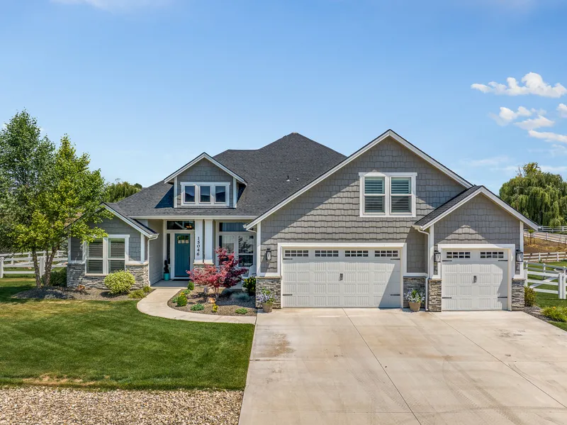 Aerial view of a luxury home in Meridian, Idaho, with a three-car garage, manicured lawn, and modern landscaping, taken using drone photography for real estate marketing.