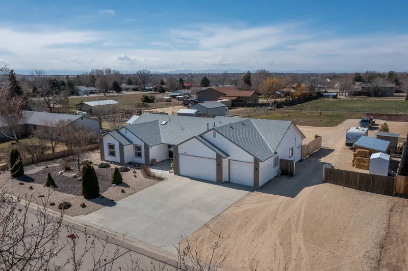 Aerial real estate photo of a Boise home with a large lot, multiple garages, and a spacious gravel driveway, showcasing open rural surroundings.
