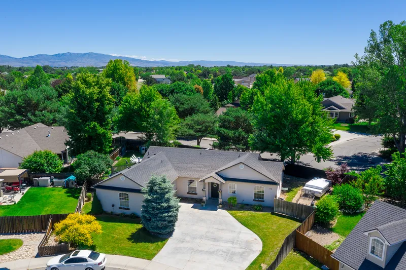 Aerial view of a Boise home in a cul-de-sac, surrounded by greenery, with a mountain range in the background.