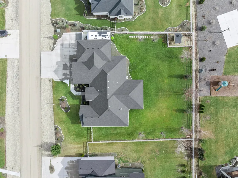 Top-down aerial view of a luxury home in Caldwell, Idaho, featuring a large backyard, landscaped lawn, and a private driveway in a high-end neighborhood.