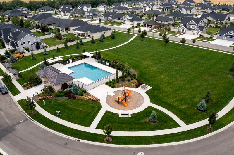 Aerial real estate shot of an upscale Eagle, Idaho neighborhood highlighting a community pool, park, and lush landscaping. Captured using professional drone photography.