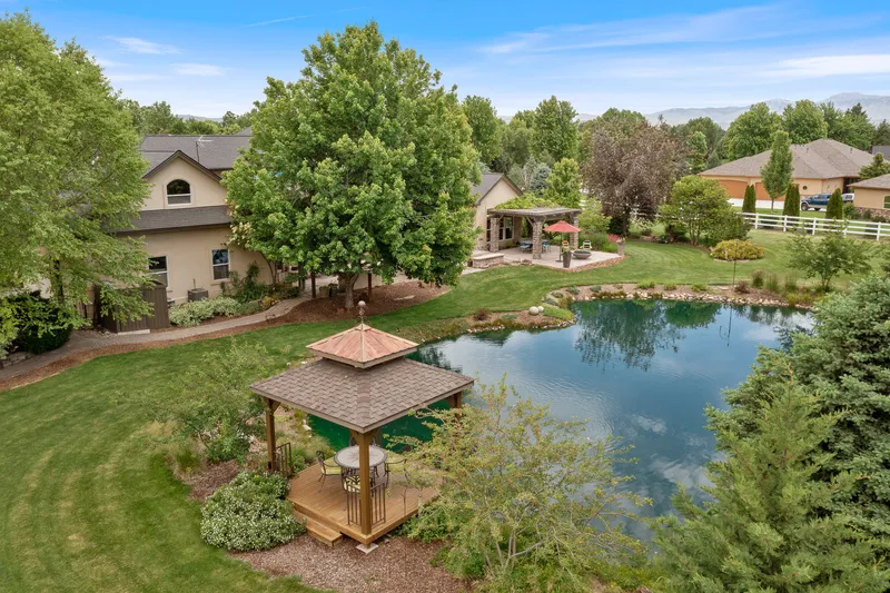 Aerial view of a luxury estate in Eagle, Idaho, featuring a private pond, gazebo, and manicured landscaping, captured with professional drone photography for real estate marketing.