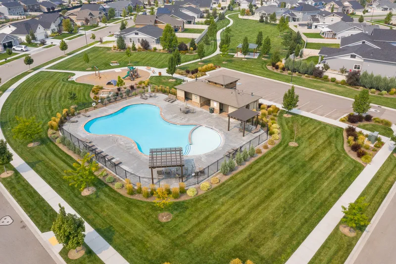 A high-resolution aerial snapshot of a Meridian, Idaho neighborhood featuring a beautifully designed community pool, manicured lawns, a playground, and surrounding homes, highlighting the area's inviting atmosphere.