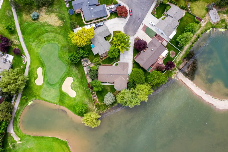 Aerial view of a waterfront home in Meridian with golf course views, a private lake, and a well-manicured backyard—perfect for luxury home listings, drone real estate photography, and Idaho property marketing.