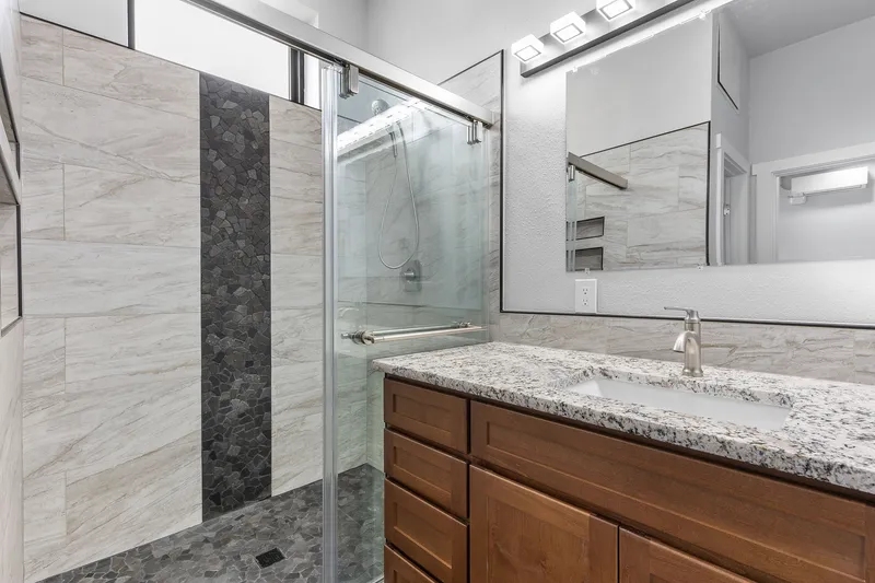 Modern bathroom with walk-in shower, granite countertop, and wood vanity in Boise