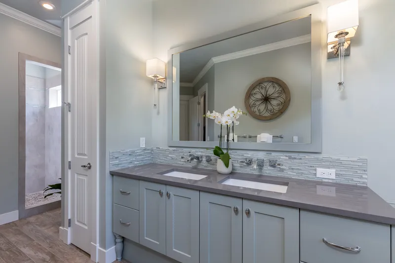 Modern double vanity in an Eagle, Idaho home with soft blue cabinetry, tile backsplash, and elegant lighting, captured for real estate marketing.
