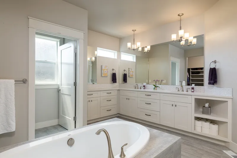 Spacious bathroom in Eagle home with a soaking tub, double vanity, modern lighting, and a large mirror, professionally photographed for real estate marketing.