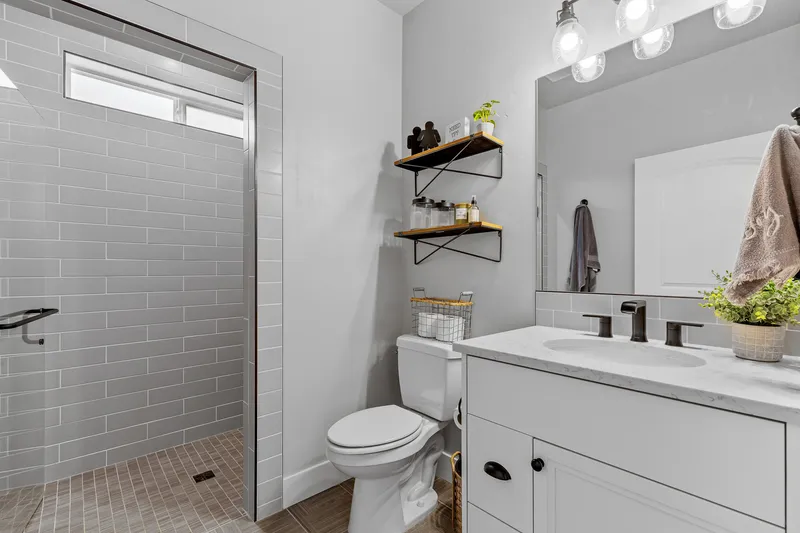 Modern guest bathroom in Star, Idaho, featuring a walk-in shower with gray subway tiles, white vanity, and black fixtures, professionally photographed for real estate listings.