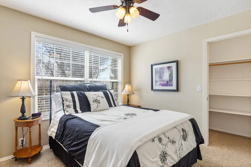 Boise bedroom with large windows, modern ceiling fan, and a cozy bed, perfect for real estate listings and home staging photography.