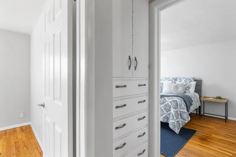 Interior view of a Boise Bench home showing a hallway with built-in storage and a bedroom with blue bedding and hardwood floors. Ideal for real estate photography and home listings in Boise, Idaho.