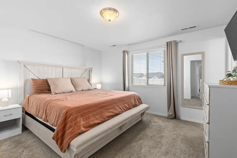 Cozy bedroom with king-sized bed, neutral tones, and natural lighting in Meridian, Idaho, ideal for short-term rental listings on Airbnb and Vrbo.