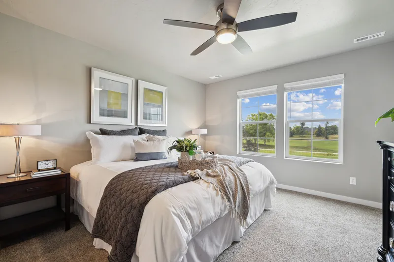 Modern bedroom in Kuna with a neutral color scheme, large windows showcasing outdoor views, and a cozy, well-styled bed with decorative accents.