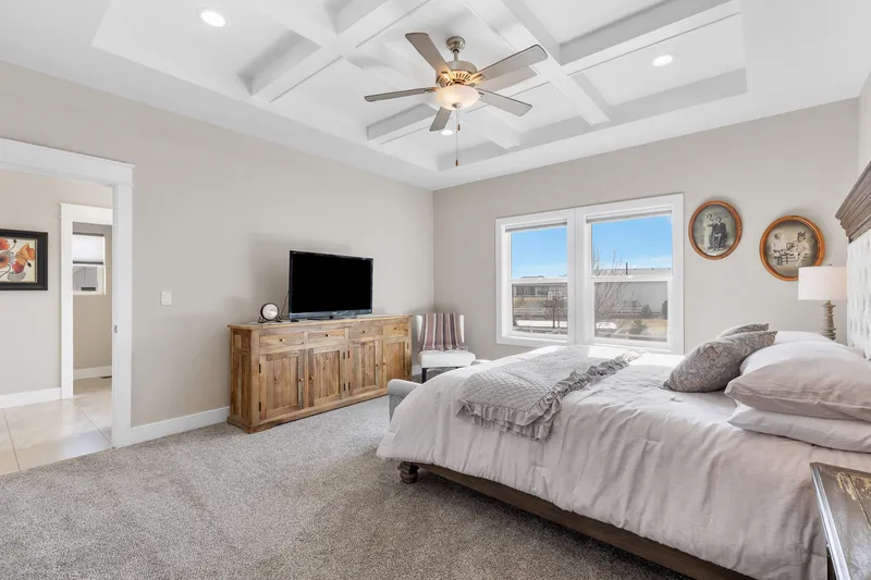 Spacious master bedroom with a coffered ceiling, large windows, and neutral decor—perfect for real estate listings and marketing visuals.