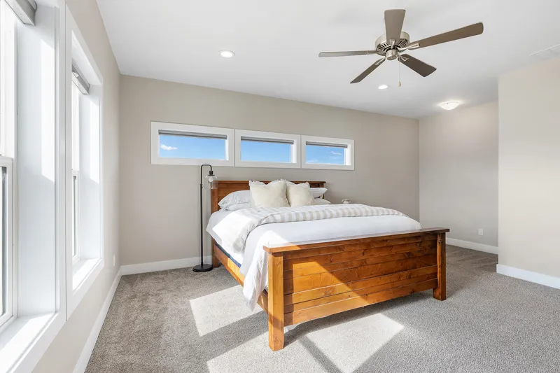 Bright modern bedroom with large windows, neutral decor, and natural light—professionally photographed for real estate marketing and short-term rental listings.
