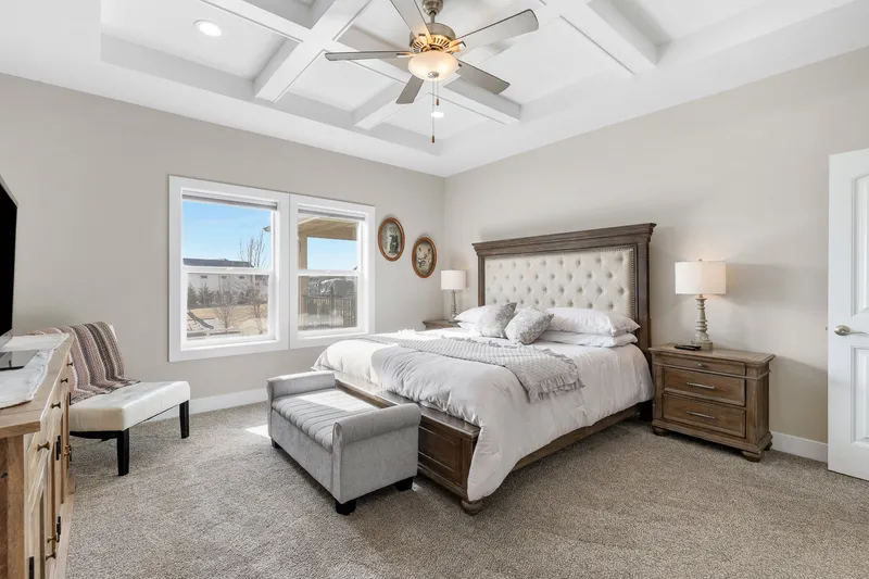 Bright and inviting master bedroom with coffered ceiling, large windows, and elegant furnishings—captured for real estate marketing and short-term rental promotion.
