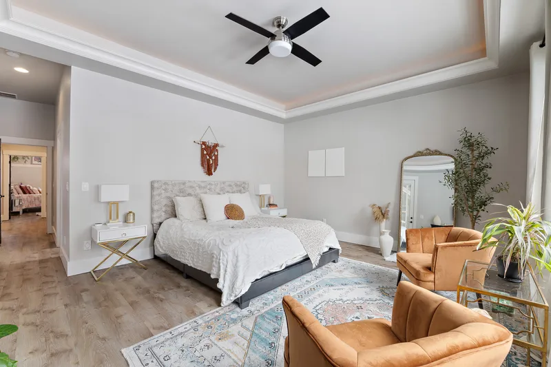 A spacious master bedroom in Star, Idaho, featuring a king-size bed, accent chairs, soft neutral tones, and large windows, professionally photographed for real estate marketing.