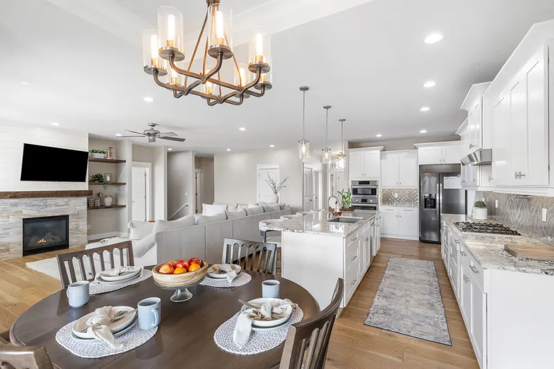 Bright and spacious open-concept kitchen and living room in a Caldwell, Idaho home, featuring white cabinetry, granite countertops, a fireplace, and modern lighting.