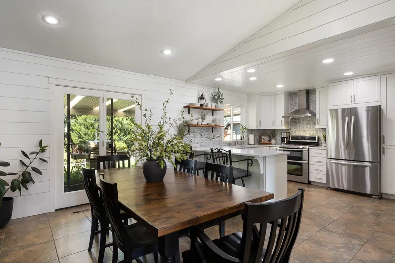 Modern farmhouse kitchen and dining space in Nampa, Idaho, with shiplap walls, a rustic wood dining table, and stainless steel appliances.
