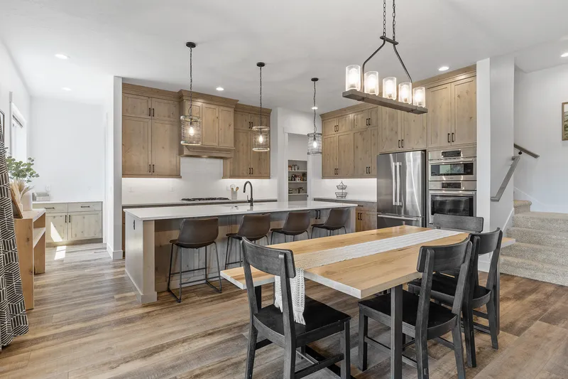 Rustic kitchen and dining area in Star, Idaho, with wood cabinetry, pendant lighting, and modern appliances, professionally photographed for real estate marketing.