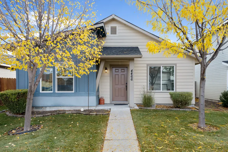 A charming single-story home in Garden City, Idaho, framed by vibrant yellow fall leaves, professionally photographed to highlight curb appeal and seasonal beauty.