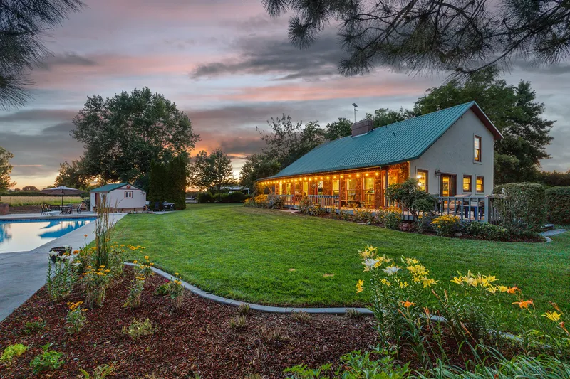 Twilight poolside photo of a luxury home in Nampa, Idaho, with a cabin-style home, pool, and gazebo.
