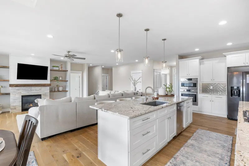 Open-concept kitchen and living room in a Caldwell, Idaho home, featuring a large island, granite countertops, stainless steel appliances, and a cozy fireplace.