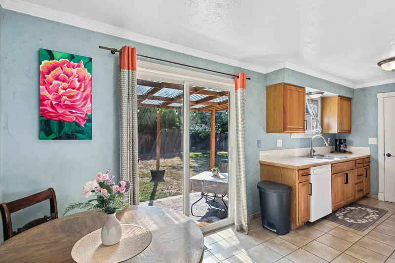 Garden City kitchen with natural light, wooden cabinets, tile flooring, and a sliding glass door leading to an outdoor patio.