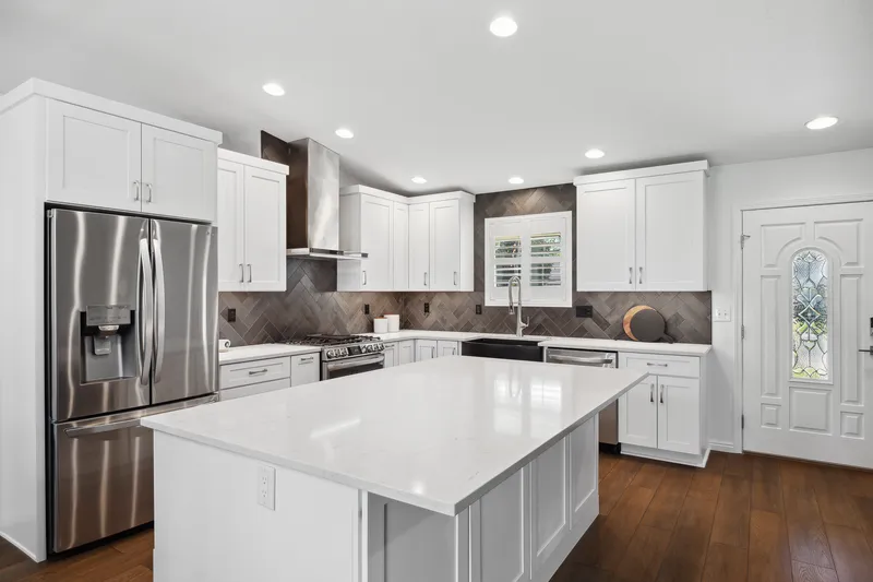 Bright white kitchen with a large island and dark herringbone backsplash in Kuna, Idaho.