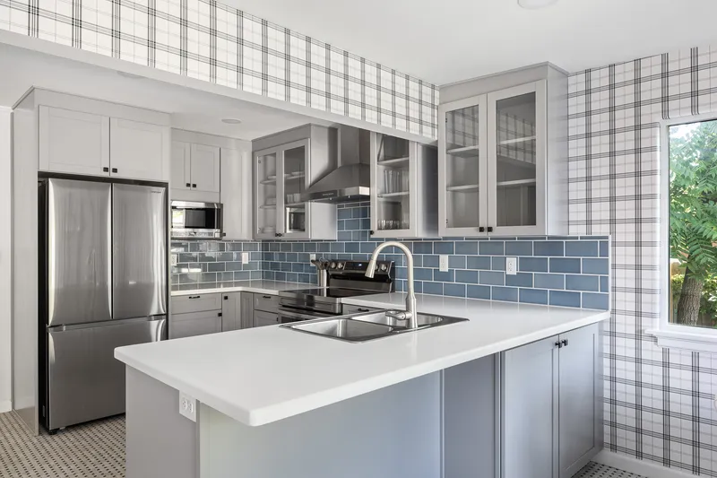 Modern kitchen with blue backsplash, white island, and gray cabinets in Nampa, Idaho.