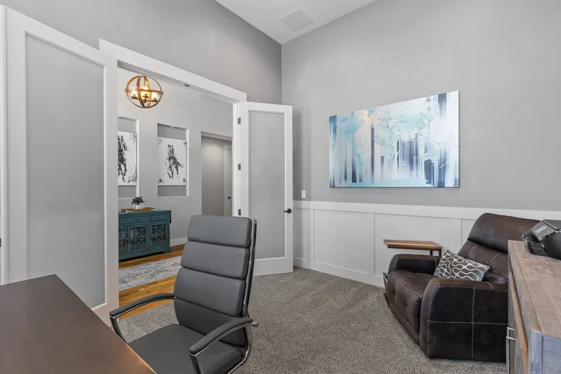 Modern home office in Middleton, Idaho, featuring frosted glass doors, gray walls, a leather recliner, and professional real estate photography.